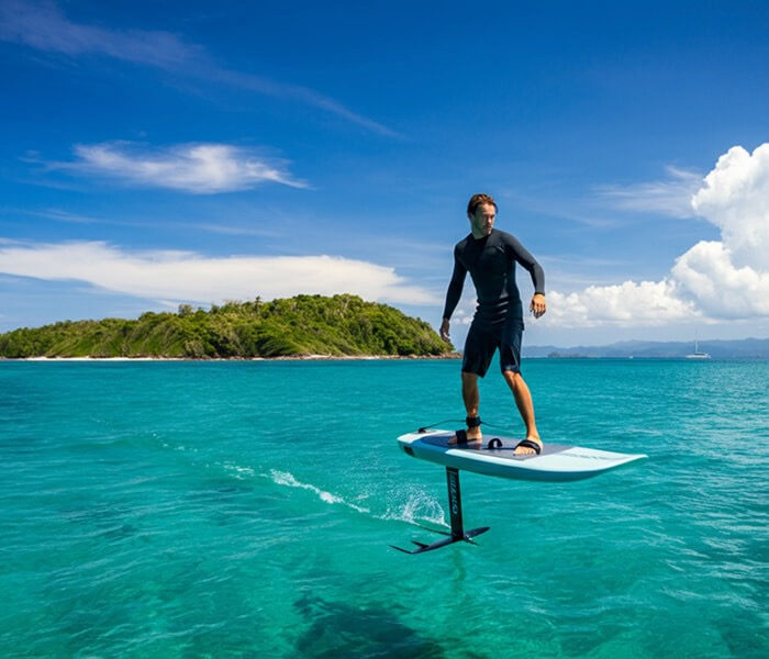 E-foil electric surfboard above turquoise water near tropical island, Koh Phangan
